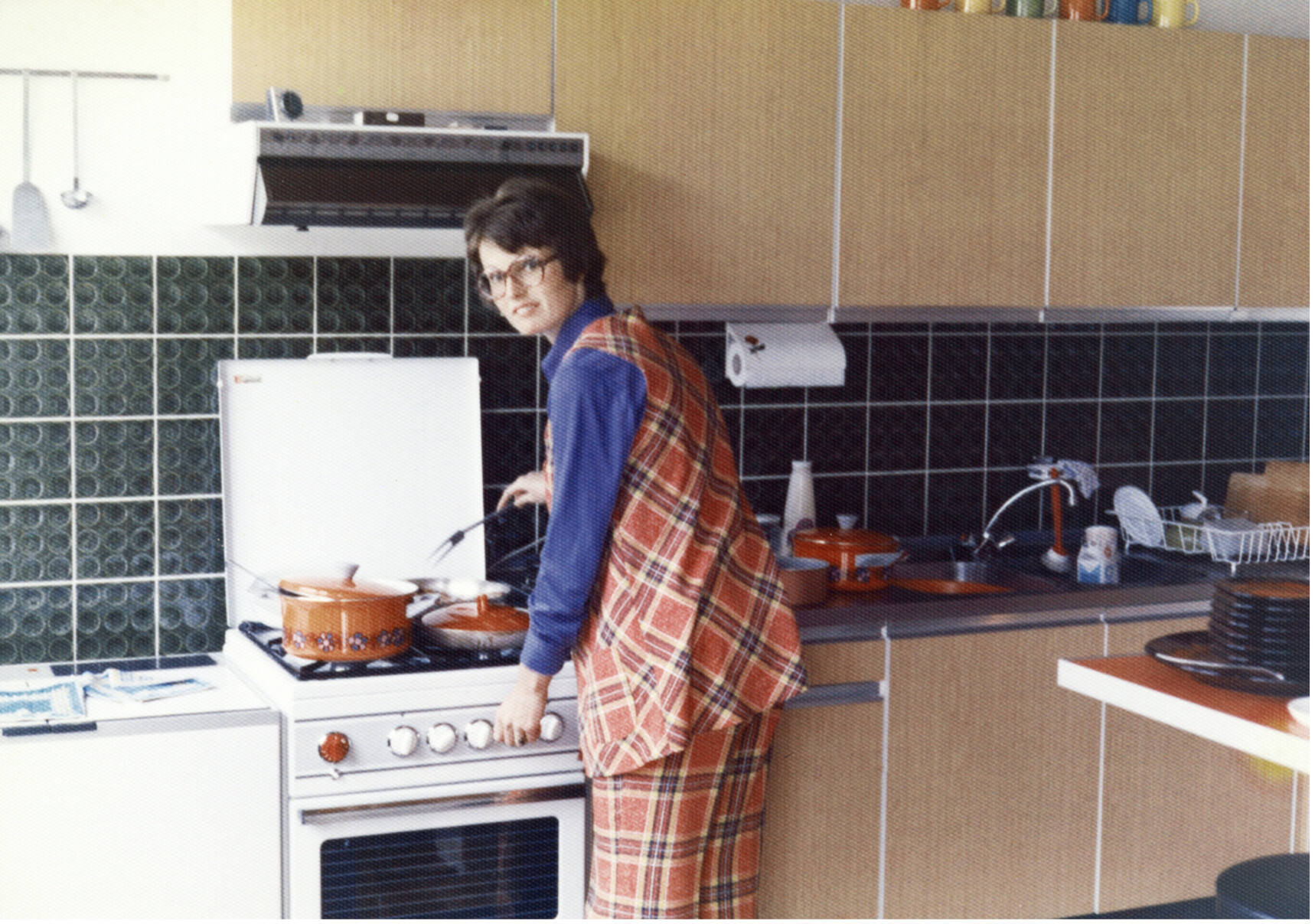 Housewife cooking at gas stove in early 1970's. Stock photo.